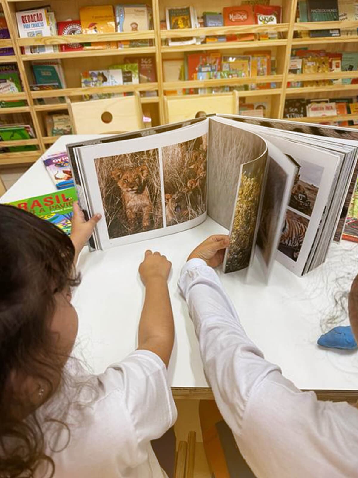 Propósito Educacional - crianças folheando livro na biblioteca