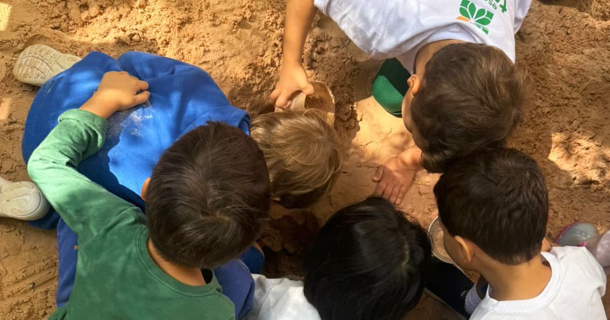 Educadores acompanham crianças reunidas em uma atividade de aprendizagem e criação em sala de aula